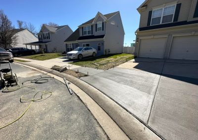 Freshly poured concrete driveway in front of a suburban house on a sunny day, with equipment nearby.
