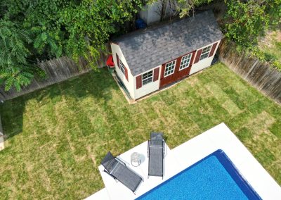 A backyard with a shed, two lounge chairs, and a pool, viewed from above.