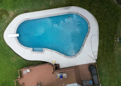 A backyard swimming pool with a diving board and deck, viewed from above.